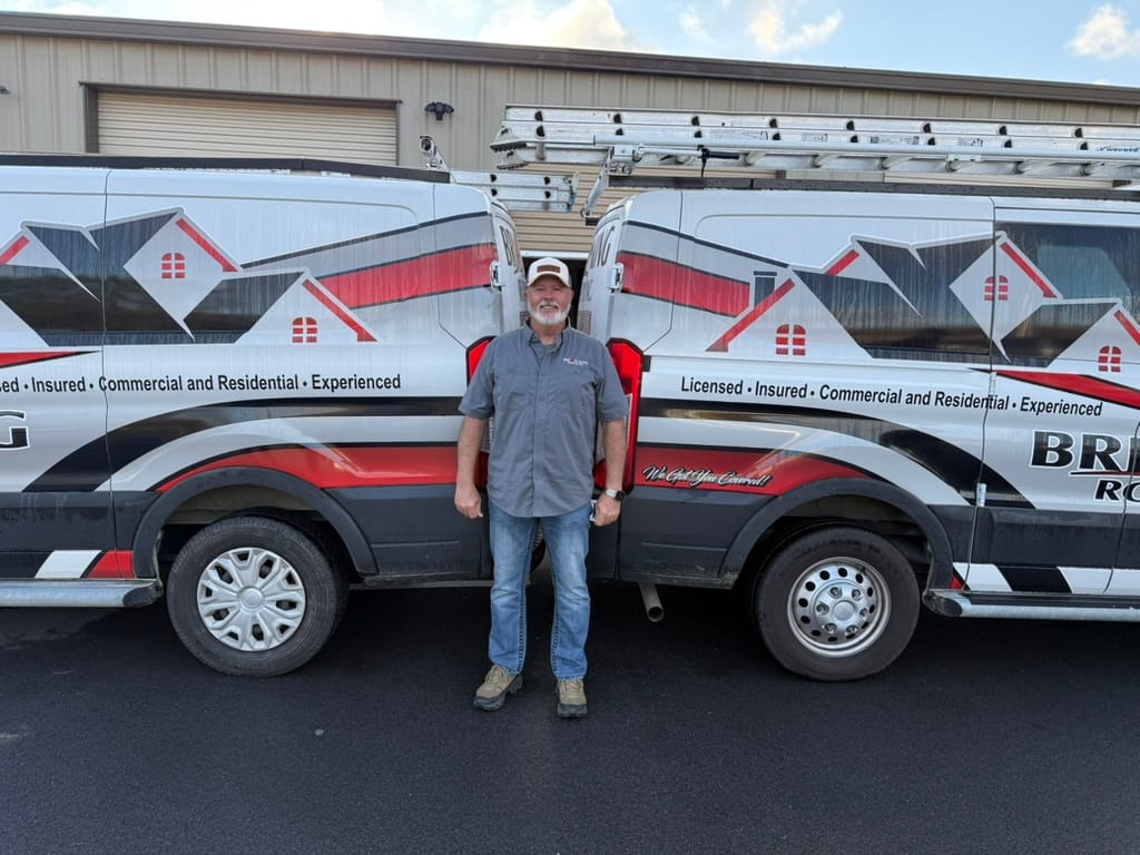 Brian King in front of two Brian King Roofing vans at the shop in Seymour, Tennessee